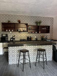 a kitchen with two bar stools and a counter at D&B apartments in Lo de Marcos