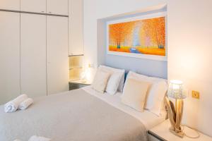 a bedroom with a white bed with a painting on the wall at Front Lake Apartment Rainer in Bardolino +20 photos