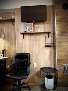 a black chair and a table and a television on a wall at Cozy in Sarajevo