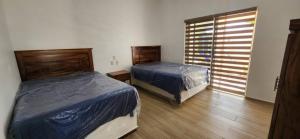 a bedroom with two beds and a window at Meztli Beach House in La Manzanilla