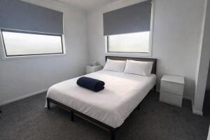 a bedroom with a bed with a blue pillow on it at Spacious Private 4BR Upper Floor Sleeps 8 Spa Free parking in Werribee