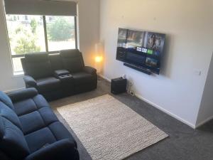 a living room with a couch and a flat screen tv at Spacious Private 4BR Upper Floor Sleeps 8 Spa Free parking in Werribee