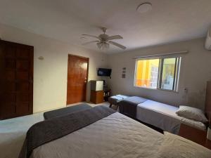 a bedroom with two beds and a ceiling fan at Casa Bugambilia Progreso #4 in Progreso
