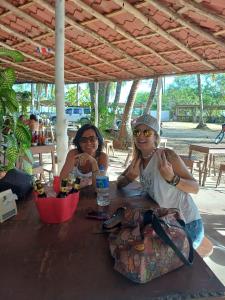 two people sitting at a table with a bottle of water at Passiflora Backpackers Samara in Sámara