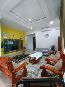 a living room with chairs and a table and a couch at D'Beris Homestay in Bachok