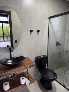 a bathroom with a black toilet and a sink at Refúgio do Morro - cabana 2 in Torres