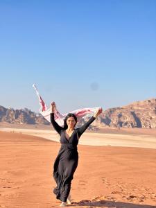 a woman in a black dress running on the desert at Jihad camp in Disah