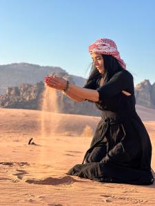 a woman sitting in the sand in the desert at Jihad camp in Disah