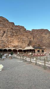 a building with a fence in front of a mountain at Red sand tent in Disah