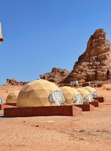 a row of domes in the middle of a desert at Red sand tent in Disah