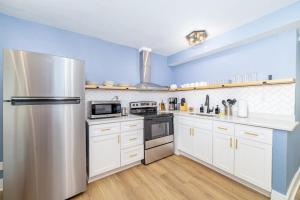 a kitchen with white cabinets and a stainless steel refrigerator at Sojourn's Harborage 2 BR 1 BA in Norfolk