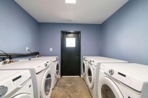 a laundry room with three washing machines and a black door at Sojourn's Harborage Pet-Friendly # 3 in Norfolk