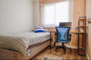 a bedroom with a desk and a bed and a chair at Acogedora casa cerca del mar in San Pedro de la Paz