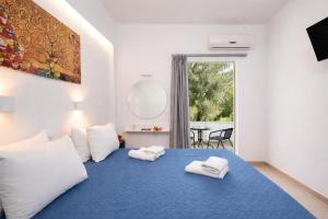 a bedroom with a blue bed with towels on it at Afroditi Hotel in Plakias
