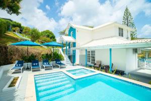 a pool with chairs and umbrellas next to a house at Paradise Haven Saint Lucia in Corinthe