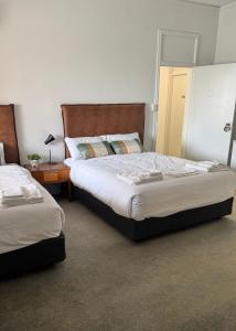a bedroom with two beds and a table with a lamp at Amaroo Hotel Dubbo in Dubbo +3 photos
