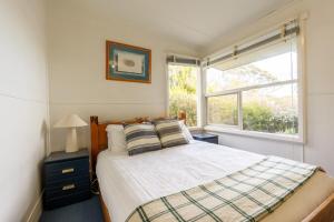 a bedroom with a bed and a window at The Shack - Beachside At Binalong in Binalong Bay