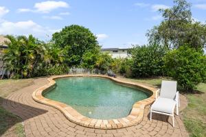 a small swimming pool with a chair and a table at Pukeko Guesthouse - Relax in Redcliffe in Redcliffe
