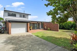 a house with a garage and a brick wall at Pukeko Guesthouse - Relax in Redcliffe in Redcliffe