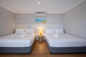 two beds in a small room with a lamp at Saltwater Villas - Pet Friendly Accommodation in Mooloolaba