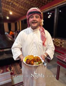 a man is holding a plate of food at Bedouin Nights Camp in Wadi Rum +113 photos
