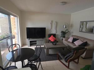 a living room with a couch and a flat screen tv at Crystal Waters 7 Ocean Corridor Views, Restaurants, Town Centre in Forster