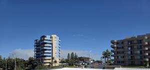 two tall buildings in a city with a blue sky at Crystal Waters 7 Ocean Corridor Views, Restaurants, Town Centre in Forster