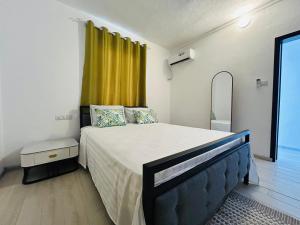 a bedroom with a large bed and a yellow curtain at MLQ Apartments by Avi in Grand-Baie
