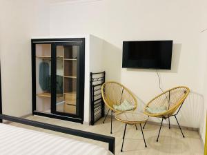a bedroom with two chairs and a tv on a wall at MLQ Apartments by Avi in Grand-Baie