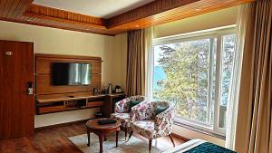 a living room with a tv and a chair and a window at The Retreat Mashobra, Shimla in Shimla