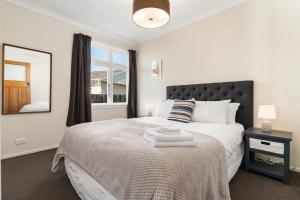 a bedroom with a bed with a black headboard and a window at Sunset Villa in Martinborough +25 photos