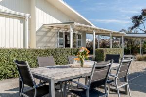 a table with chairs and a vase of flowers on it at Sunset Villa in Martinborough