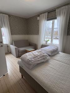 a bedroom with two beds and a couch and a window at Södra Ljunga Vandrarhem in Ljungby
