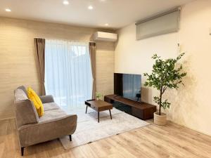 a living room with a chair and a television at Akikawa Koshi 13 新築木造一棟貸切ヴィラ in Yuge