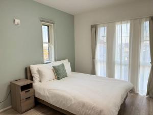 a bedroom with a white bed with a window at Akikawa Koshi 13 新築木造一棟貸切ヴィラ in Yuge