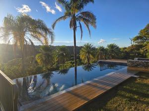 a pool with palm trees and a wooden deck at Hotel Mango Valley in Grecia
