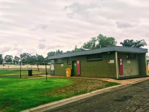 a green building with red doors in a field at Temora Motel - UNDER NEW MANAGEMENT in Temora