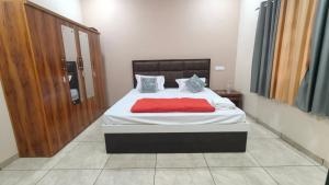 a bedroom with a bed with a red blanket on it at Vasant Vihar Farm House in Silvassa