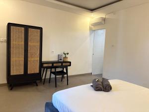 a bedroom with a bed and a desk with a table at Umah Sepur Villa in Dalung