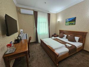 a hotel room with a bed and a desk and a television at Maximum Hotel in Navoi
