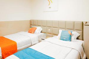 two beds in a hotel room with orange and blue at SANS Hotel Joy Inn Brebes in Ketanggungan