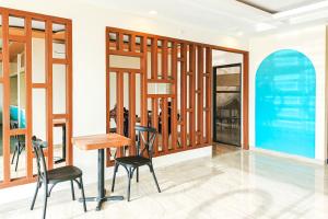 a table and two chairs in a room with windows at SANS Hotel Joy Inn Brebes in Ketanggungan