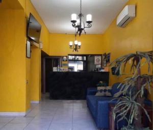 a living room with a blue couch and yellow walls at Hotel PREMIER in Linares