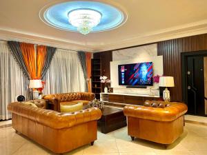 a living room with leather furniture and a flat screen tv at 3R Haven in Kumasi