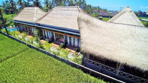 a building with a straw roof with plants in a field at Junjungan Serenity Villas & Spa in Ubud