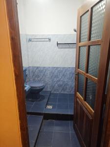a bathroom with a toilet and a door at Bloomy villa in Hatton