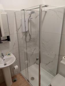a shower with a glass door next to a sink at Lantern Guest House in Edinburgh +20 photos