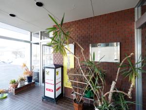 a brick wall with potted plants in a room at Tabist Hotel New Nemuro in Nemuro