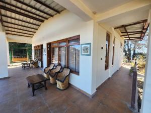 a porch of a house with a table and chairs at Mangat Farm, Kanatal in Kanatal