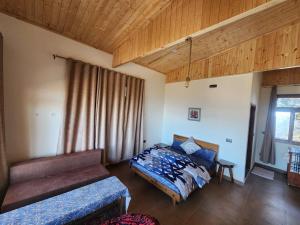 a bedroom with a bed and a couch and a window at Mangat Farm, Kanatal in Kanatal